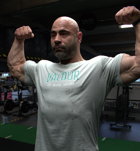 bodybuilder doing a front double bicep pose in valour shirt