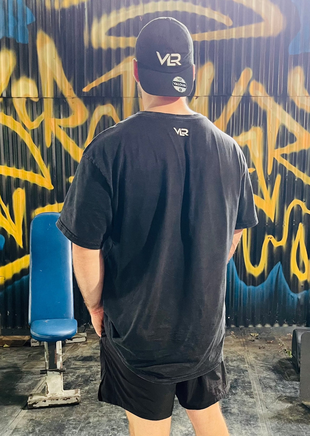 man wearing black dad cap infront of graffiti wall