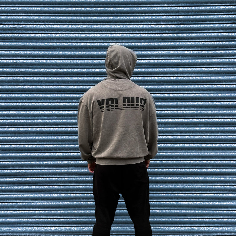 man in grey acid wash hoodie in front of steel shutters